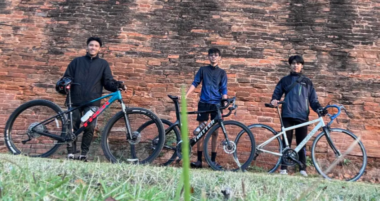 Jackson and Liam with bikes by the brick wall